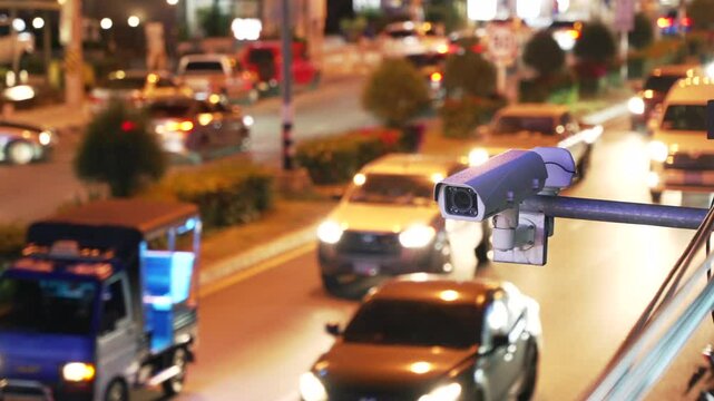 City traffic monitoring camera and speed control above the asphalt road with many blurred cars at night. 