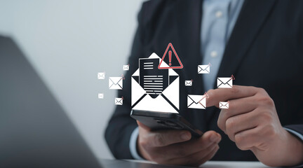Businessman receives a suspicious email alert on his smartphone, representing phishing or spam risk in a digital workspace environment