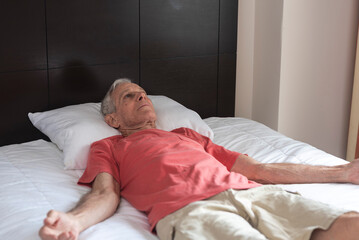 An old but fit man doing Savasana or Corpse Pose at his hotel room. A peaceful moment of mindfulness and relaxation.
