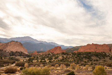 Naklejka premium Garden of the Gods rock formations glow under afternoon sun with sparse trees and desert terrain