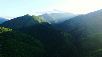 Cinematic sunset aerial over green Apennine valleys, steep forested peaks, Italy