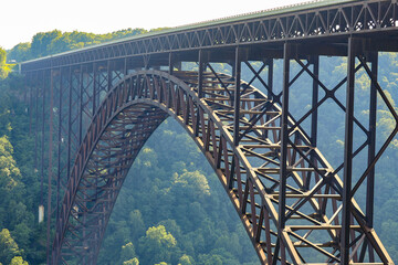 Long view of historic steel railway bridge disappearing into misty forested valley under diffused daylight