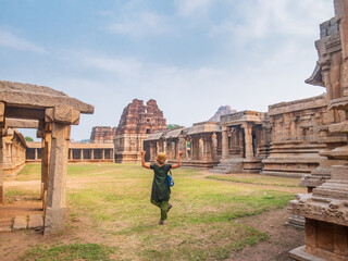 Woman exploring amazing temple complex at Hampi, world famous unesco site. Tourist walking among ruins stone walls gateways in Karnataka, India