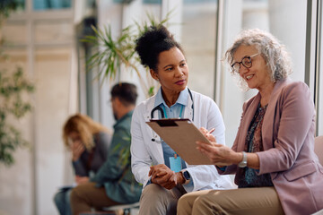 Black doctor and her female patient analyzing medical report after examination at polyclinic.