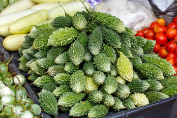 A pile of green vegetables including cucumbers and tomatoes