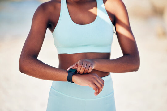 Black woman, hands and smart watch on beach for fitness, step count and activity tracking for exercise progress. Girl, stopwatch and time management for workout session, monitor heart and health app.