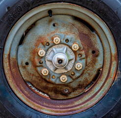 Close-up view of a rusty wheel rim with visible bolts and texture, capturing the effects of time and exposure in natural light.