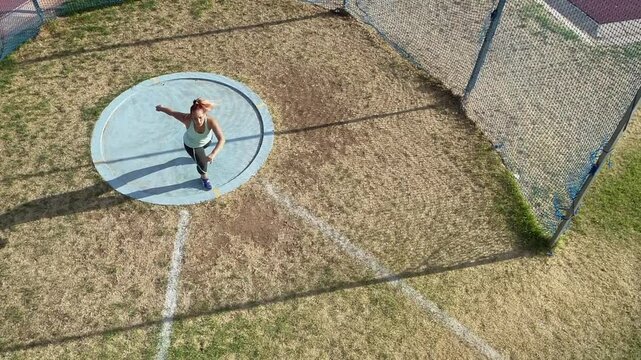 Young woman demonstrates spin technique for throwing discus, aerial