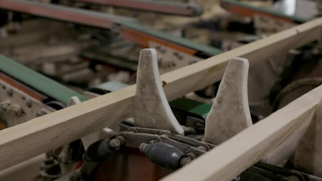 Wooden planks moving through an industrial roller conveyor system at a sawmill or timber processing plant, showing part of the automated sorting and transport line