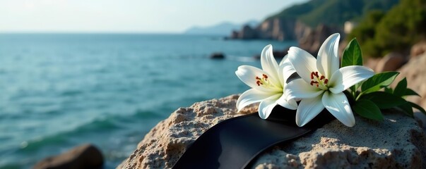 Black funeral ribbon and white lily flowers placed delicately on a weathered rock overlooking the tranquil sea,  mourning,  remembrance