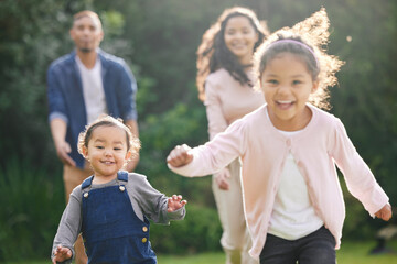 Family, garden and kids running with parents and fun game with love, support and care outdoor. Lawn, backyard and nature with baby, mom and dad together with bonding and weekend activity on park walk