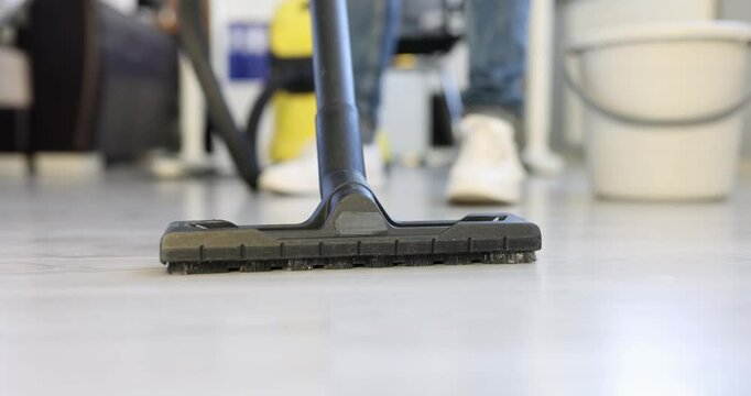Maid hoovers parquet floor with powerful appliance at home. Housewife cleans room with modern vacuum cleaner brush doing chores. Housekeeping routine