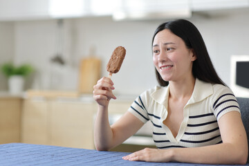 Asian woman looking at chocolate ice cream at home