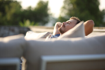 Relaxed man sitting in an exterior sofa in a terrace