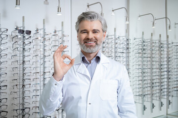 Smiling bearded mature man in lab coat feeling contented and successful