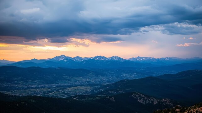 A wide-angle view showcases a snowy mountain range illuminated by twilight. Dark clouds enhance the vibrant peaks, creating a peaceful yet awe-inspiring atmosphere