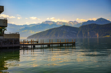 A peaceful sunset over a wooden jetty on Lake Lucerne in Weggis, Switzerland, with reflections on...