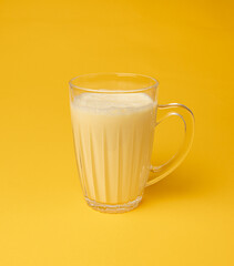 Vanilla milk shake in glass. Milkshake on yellow background, white whey protein smoothie