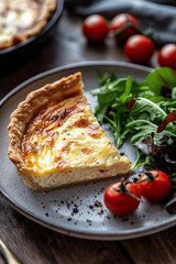 Classic Quiche Lorraine slice with fresh green salad and cherry tomatoes on a rustic plate