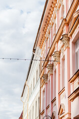 A charming European street lined with pastel-colored historic buildings, ornate architectural details, and a nostalgic atmosphere under a soft daylight sky
