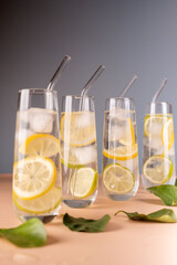 refreshing arrangement of lemon-infused sparkling water in elegant tall glasses with ice and glass straws on a minimalistic surface with green leaves, subtle, neutral, peaceful, glassware, quench