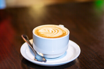 A delicious cup of cappuccino served on a saucer with a spoon
