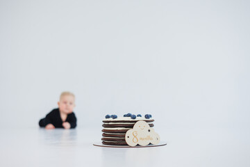 A joyful child with sparkling eyes gazes at a colorful cake against a minimalist background,...