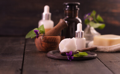 Close up of shea butter with violet flower and product for spa and relax on wooden background. Beauty spa concept. Aromatherapy, alternative medicine and perfumery concept.