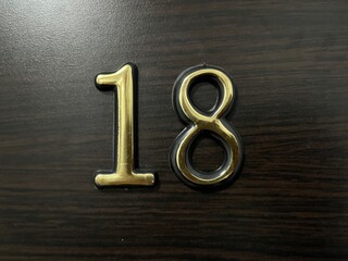 Number 18 Door Plaque Displayed on Wooden Surface