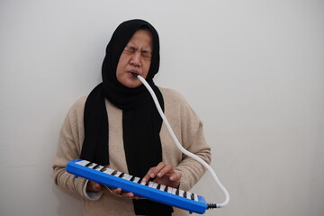 Asian muslim woman playing pianica, melodica blow organ musical intrument