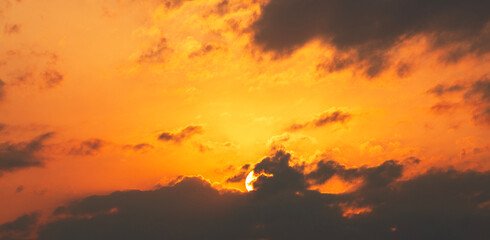 Sun sets behind the clouds, beautiful bright sunset sky with dramatic clouds. Sunset sky background.