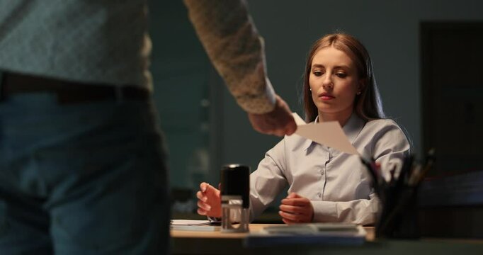 Manager brings document to woman and furious worker throws crumpled piece of paper. Tense atmosphere in office reflects anger and overwork aggression
