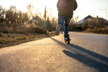 Child riding scooter on smooth rural path in golden sunlight creating peaceful, scenic lifestyle...
