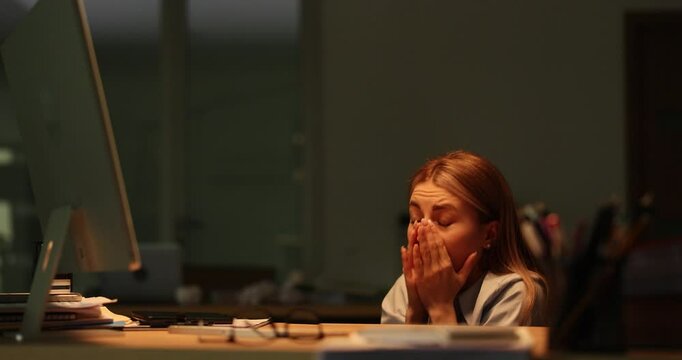 Woman afraid of thunderstorm lightning flashes covering face with hand and sitting under desk. Dim lighting workspace contribute to tense atmosphere