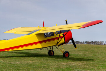 small yellow and red plane at the airport. plane standing on the green grass of the airport on a beautiful sunny day.