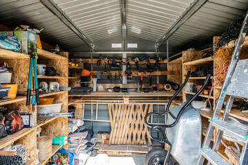 Interior view of fully stocked tool shed with organized shelves containing construction and...