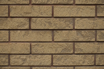 Closeup of beige split face brick veneer wall with running bond layout