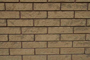Surface of beige split face brick veneer wall with running bond layout