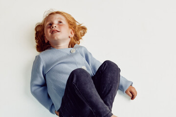 Little girl in blue sweater laying on stomach with arms outstretched in a serene moment of...