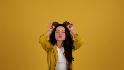 Happy woman holding oatmeal cookies above her head, having fun and dancing. Copy space, isolated on...