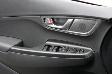 Driver door trim. Window control buttons in modern electric car. Car interior details of door handle with windows controls, Speaker and adjustments.  Modern car interior details.