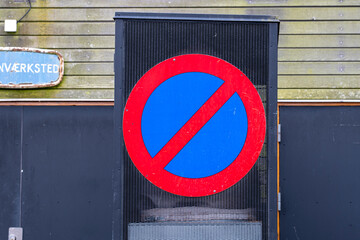No parking sign painted on metal gate in industrial urban setting, emphasizing control, restrictions, and graphic street signage in daily city environments.