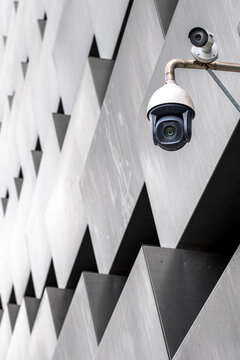 Surveillance camera mounted on patterned architectural facade, highlighting themes of urban security, public monitoring, and modern infrastructure systems.