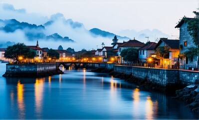 Obraz premium Night scene of a town nestled by a calm river. Lights softly illuminate buildings along the waterfront under a misty mountain backdrop.