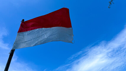 The Indonesian flag flutters in the blue sky