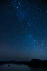 山間の湖の夜。星の煌めく空の天の川。北海道の摩周湖。