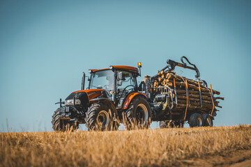 Forwarder tractor for wood transport. Tractor with trailer loaded with logs. Forestry tractor or forestry tractor for harvesting wood on the field.