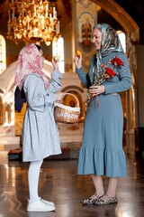 mom and daughter hold Easter eggs in the Orthodox church and pray, congratulating each other on Easter, bright Easter in the temple