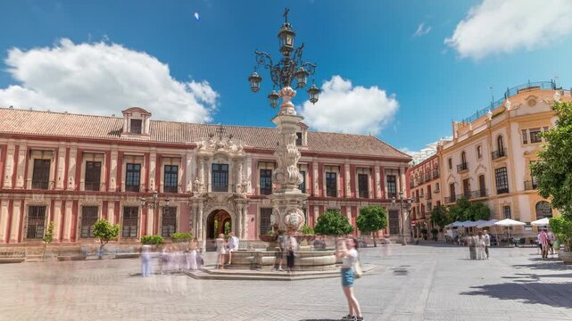 Archbishop Palace of Seville and Fuente Farola fountain on Plaza de Virgen de los Reyes city square timelapse hyperlapse. Blue cloudy sky with historic architecture. Seville, Andalusia, Spain.