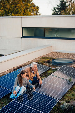 Grandfather and granddaughter working on solar panels outdoors
